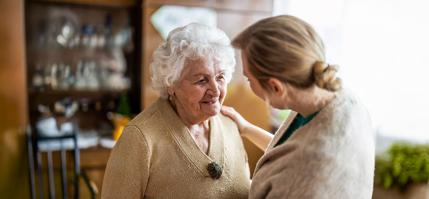 Senior woman is embraced by younger female